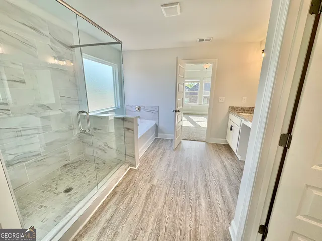 a bathroom with a granite countertop sink a mirror and shower