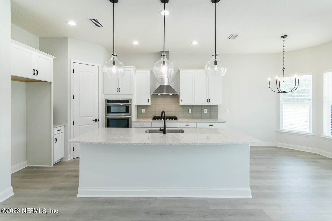 526 Eagle Moon Lake Drive St. Augustine, FL 32092 - Photo 8 of 24 a large kitchen with stainless steel appliances kitchen island a stove a refrigerator a sink and a chandelier