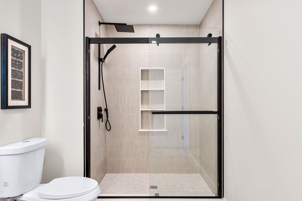 27 Guild Street, Unit 301 Boston, MA 02119 - Photo 17 of 29 a bathroom with a shower and a toilet