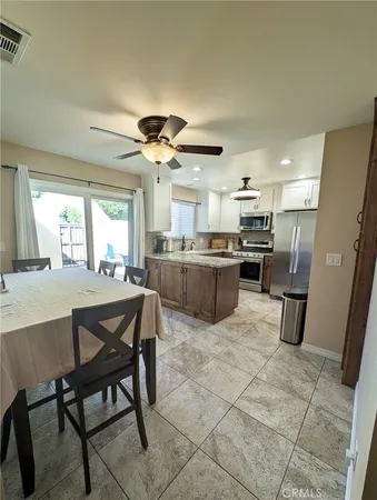 a kitchen with stainless steel appliances kitchen island granite countertop a table chairs sink and cabinets