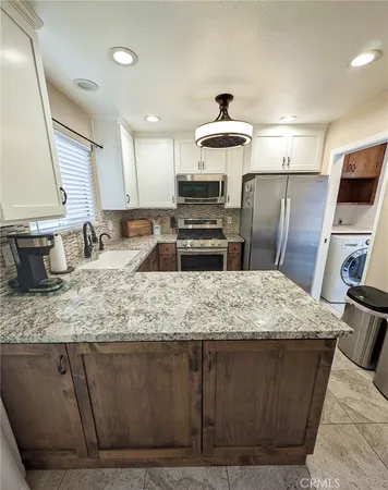 a kitchen with kitchen island granite countertop a sink stove and refrigerator