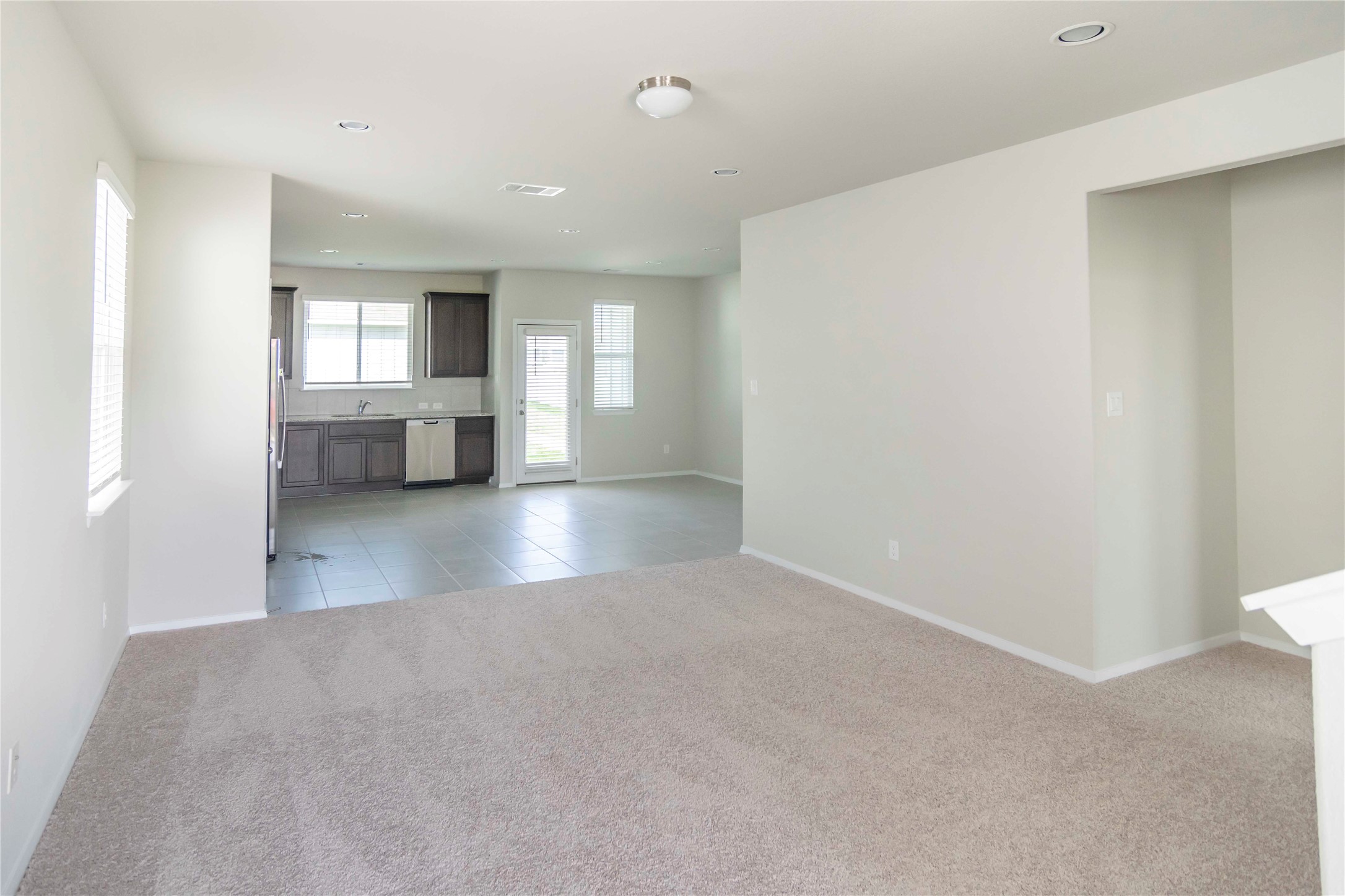 1257 Goforth Road Kyle, TX 78640 - Photo 5 of 33 Unfurnished living room featuring light carpet, recessed lighting, and light tile patterned floors