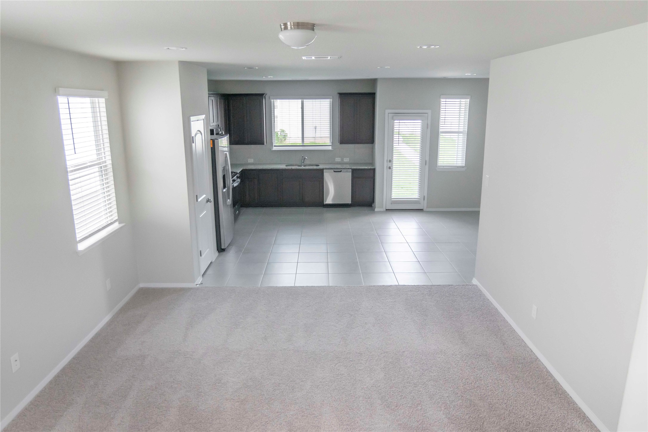 1257 Goforth Road Kyle, TX 78640 - Photo 32 of 33 Kitchen featuring light countertops, open floor plan, dark wood finish cabinets, stainless steel appliances, and light colored carpet
