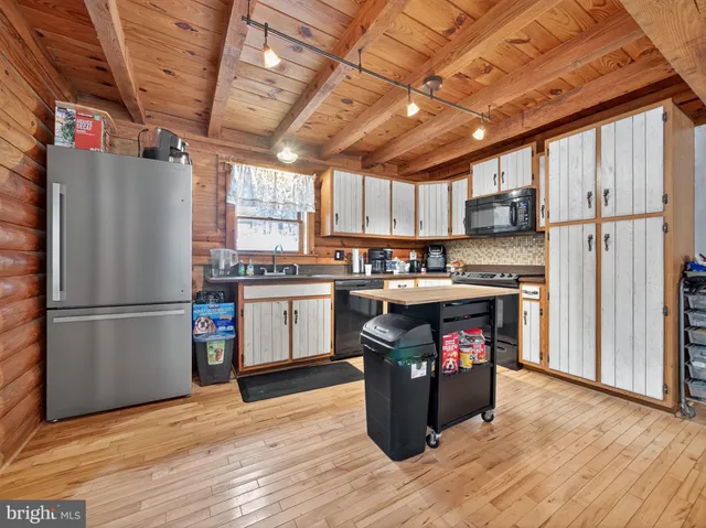 a kitchen with stainless steel appliances granite countertop a refrigerator a sink and wooden floors