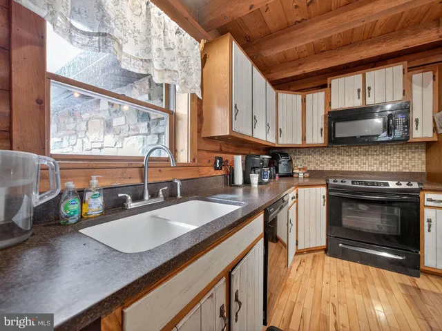 a kitchen with granite countertop a sink a counter top space appliances and cabinets