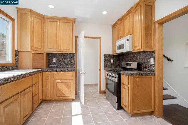 a kitchen with stainless steel appliances granite countertop a refrigerator a stove top oven and a sink