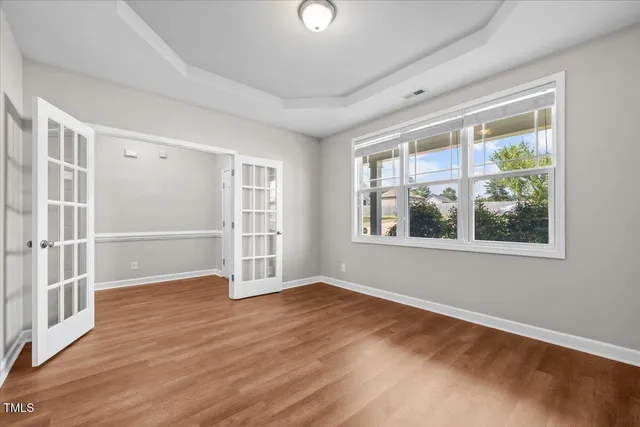 a view of an empty room with wooden floor and a window