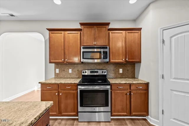a kitchen with stainless steel appliances granite countertop a sink a stove and a wooden floors