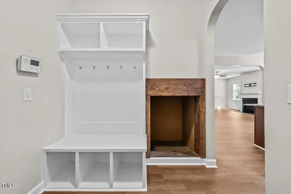 an empty room with wooden floor chandelier fan and windows