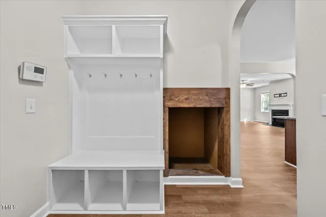 an empty room with wooden floor chandelier fan and windows