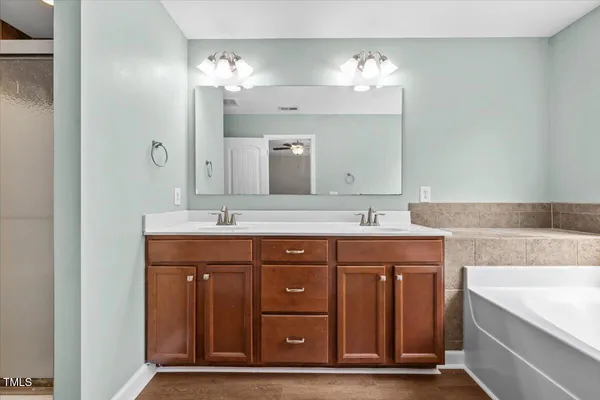 a bathroom with a double vanity sink toilet mirror and bathtub