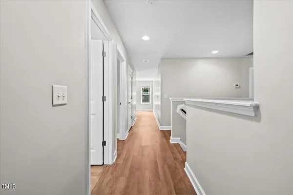 a view of a hallway with wooden floor and a bathroom