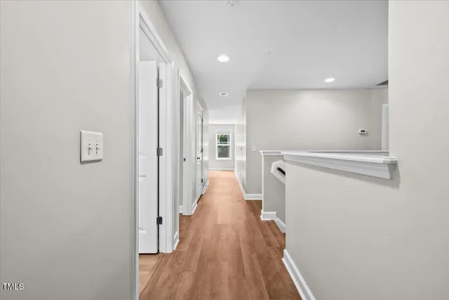 a view of a hallway with wooden floor and a bathroom