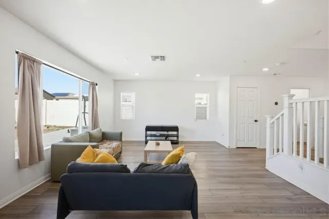 a living room with stainless steel appliances kitchen island granite countertop a refrigerator a stove and a cabinets with wooden floor