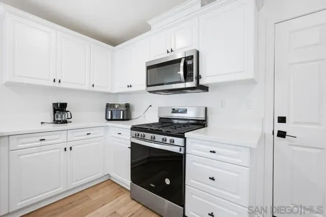 a kitchen with white cabinets and appliances