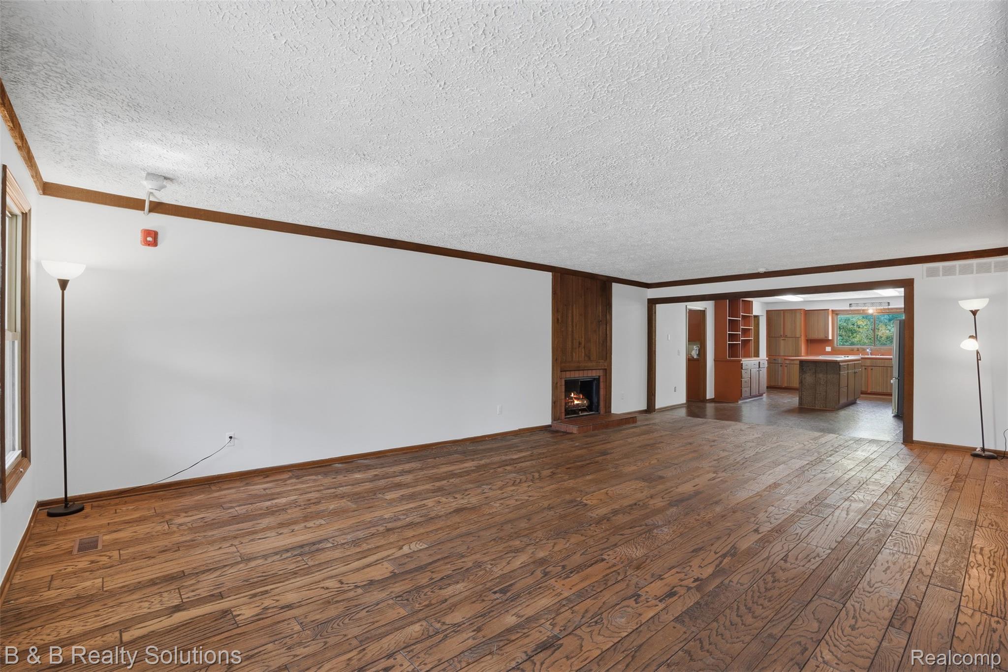 780 North Van Dyke Road, Unit APARTMENT #1 Almont, MI 48003 - Photo 6 of 28 Spacious living area featuring wood-finish flooring, a fireplace with wood paneling, and an open concept layout into the kitchen