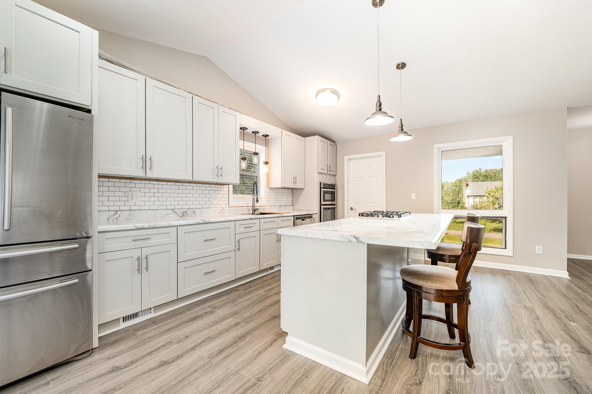 152 Sparrow Road Statesville, NC 28625 - Photo 7 of 28 a kitchen with a refrigerator a white cabinets and wooden floor