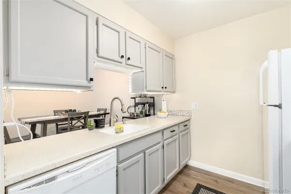 a kitchen with a sink dishwasher and cabinets with wooden floor