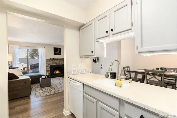 a kitchen with granite countertop a sink dishwasher stove and white cabinets with wooden floor