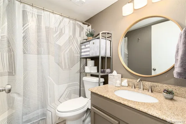 a bathroom with a granite countertop sink mirror vanity and toilet