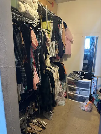 a view of walk in closet with clothes and shoes