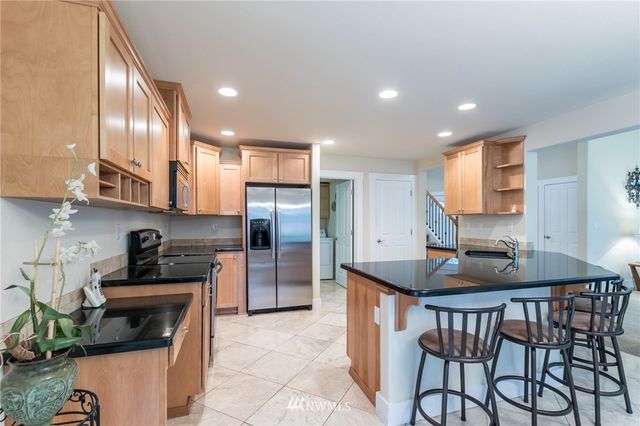 a kitchen with stainless steel appliances granite countertop a sink a stove a microwave a refrigerator and cabinets