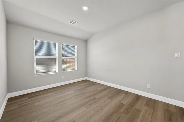an empty room with wooden floor closet and windows