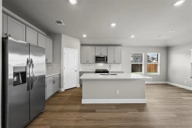 a kitchen with stainless steel appliances granite countertop a refrigerator a stove and a sink