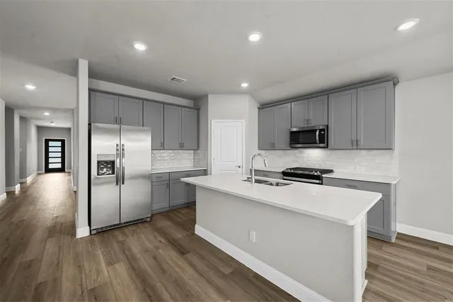 a kitchen with stainless steel appliances granite countertop a refrigerator a stove and a sink