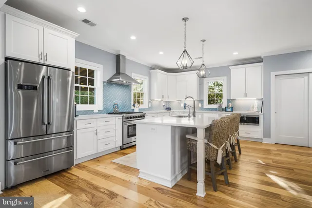 a kitchen with stainless steel appliances kitchen island granite countertop a refrigerator a stove a sink dishwasher a dining table and chairs with wooden floor