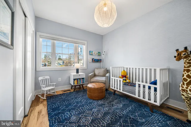 a view of a bedroom with baby bed and workspace