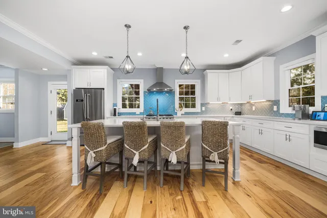 a kitchen with stainless steel appliances granite countertop wooden floors stove and white cabinets