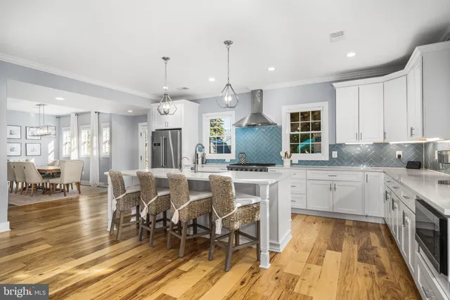 a large kitchen with cabinets chairs and wooden floor