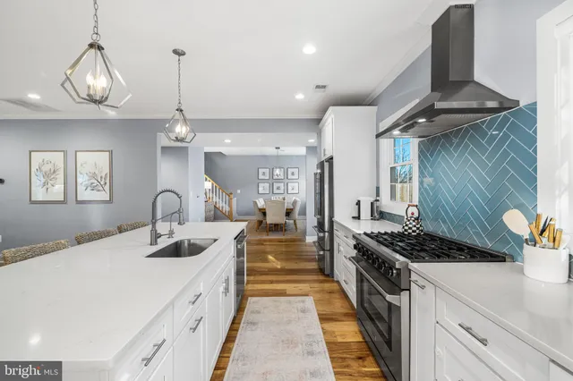 a kitchen with stainless steel appliances a stove a sink a refrigerator and chairs