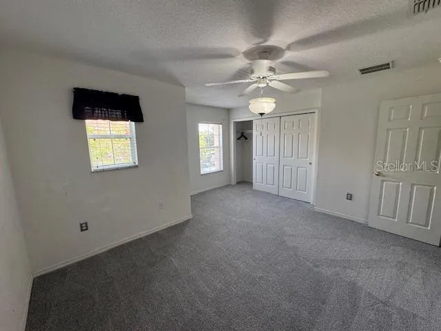an empty room with windows and fan