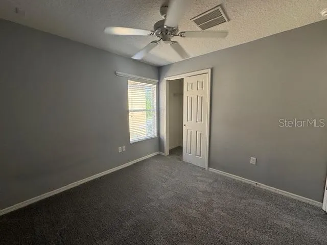 an empty room with windows and fan