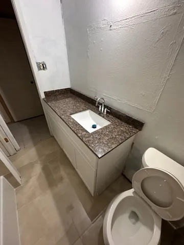 a bathroom with a granite countertop toilet and a sink