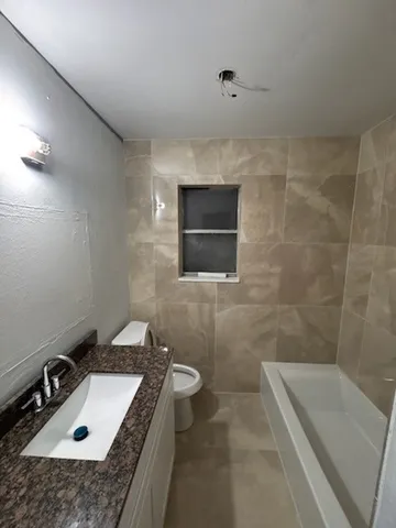 a bathroom with a granite countertop sink a toilet and bathtub
