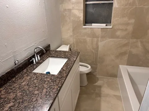 a bathroom with a granite countertop sink a toilet and mirror