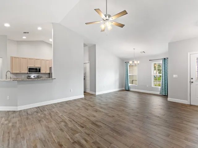 a view of an empty room with window and wooden floor