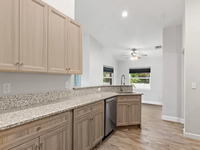 a kitchen with stainless steel appliances granite countertop a sink and dishwasher with wooden floor