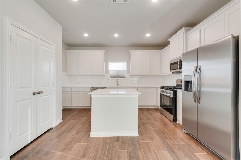 232 Sutter Mill Road Saginaw, TX 76131 - Photo 10 of 24 a kitchen with white cabinets and stainless steel appliances