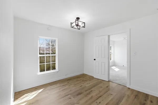 an empty room with wooden floor cabinet and windows