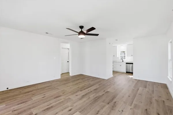 an empty room with wooden floor and a ceiling fan