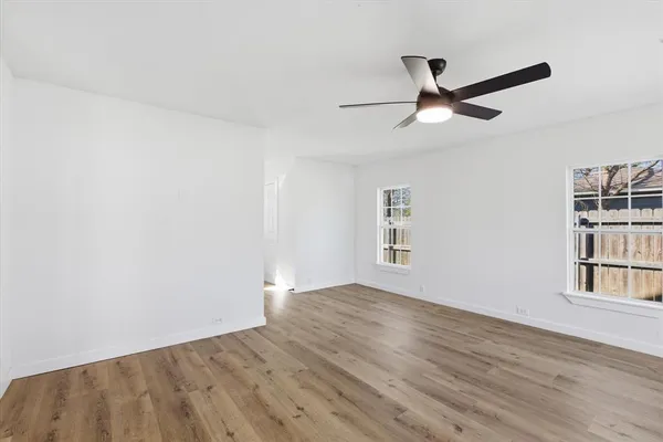 a view of empty room with wooden floor and fan