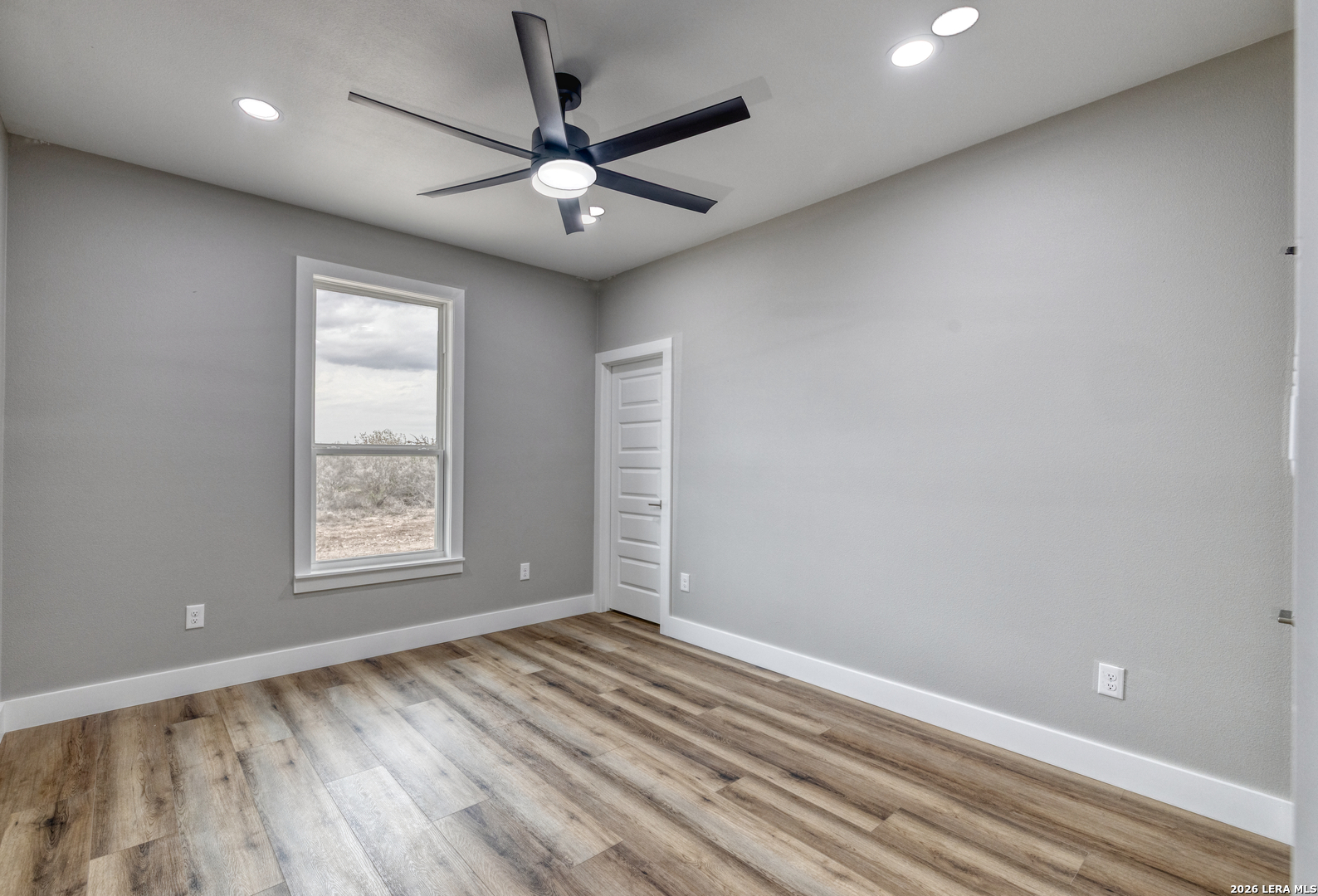 22 Greystone Hills Uvalde, TX 78801 - Photo 66 of 68 an empty room with wooden floor chandelier fan and windows