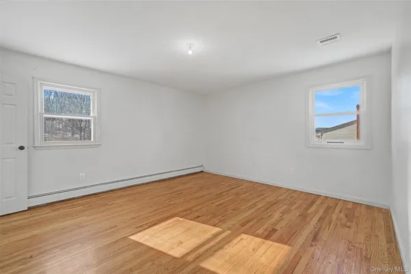 an empty room with wooden floor fireplace and windows