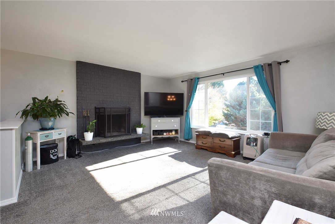 2631 166th Street Southeast Bothell, WA 98012 - Photo 2 of 18 a living room with furniture a large window and a fireplace