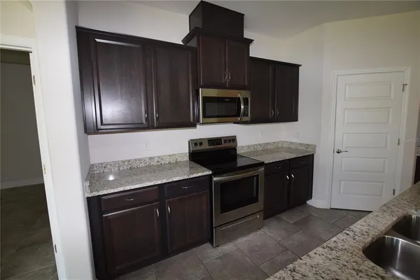 a kitchen with granite countertop stainless steel appliances stove microwave refrigerator and sink