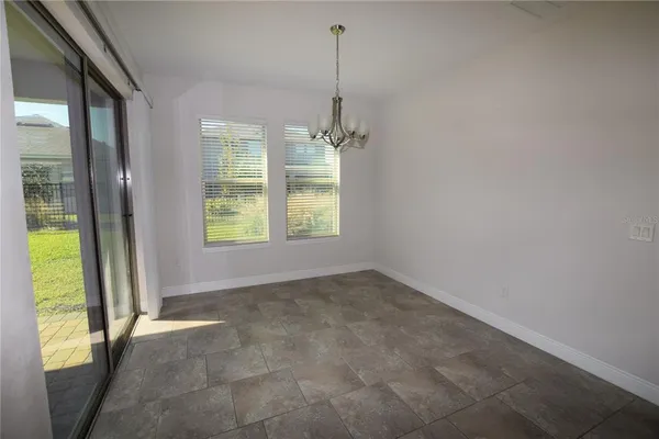 a view of an empty room with a window and a kitchen view